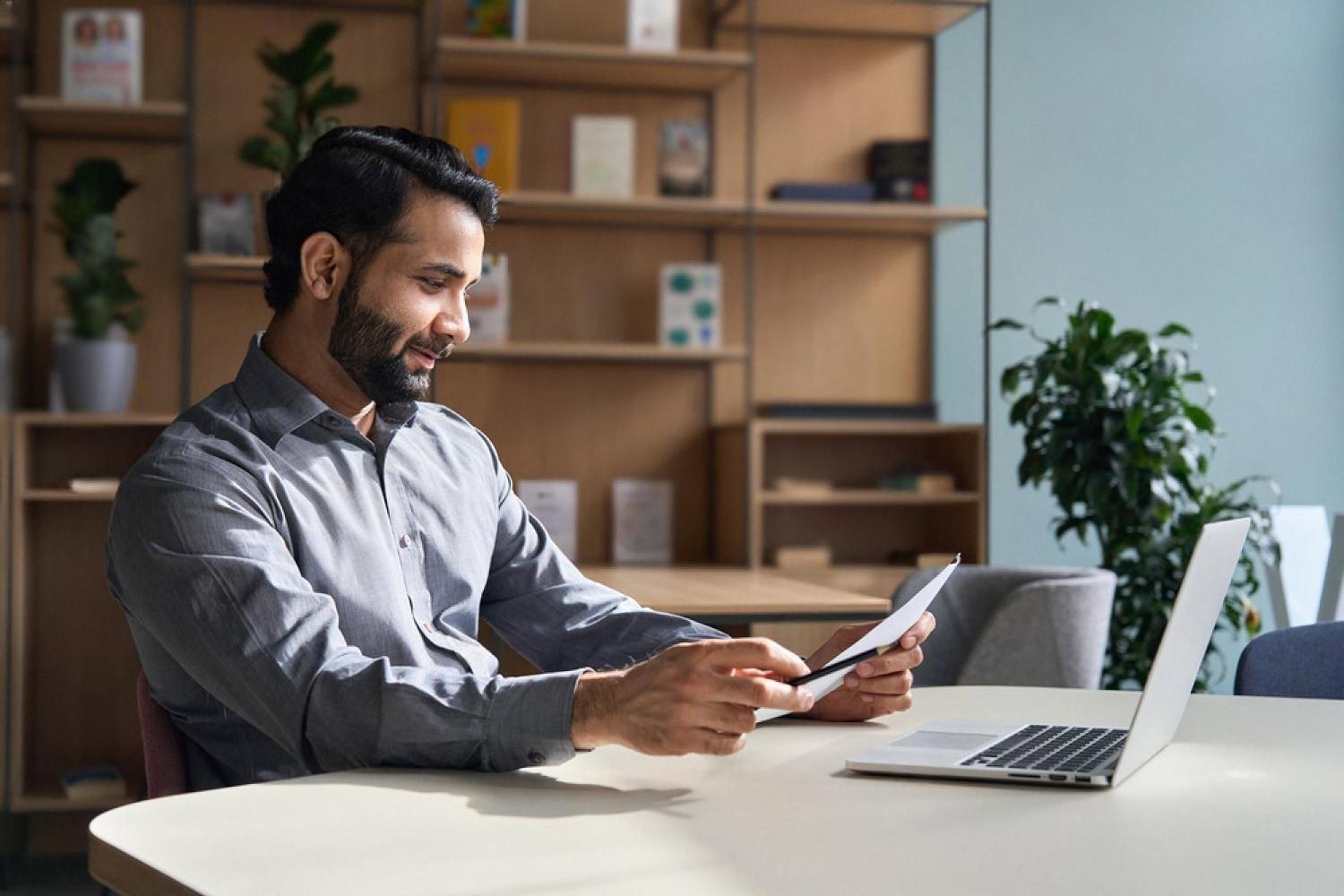 Young law graduate in a UAE office reviewing documents on a laptop